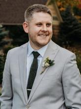 Casey McGowan smiling and wearing a gray suit. 